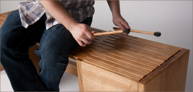 Rumble Bonk (an Idiophone Bench) 1160 - 'Rumble Bonk' provides more than a welcome rest; it has potential to create melodies and rhythms. When struck at its end with mallets, the bench produces surprising and uplifting tones. It invites you to interact with it beyond its primary use, to receive an engaging and pleasant experience. Constructed out of oak, it is suitable for interior or exterior applications.